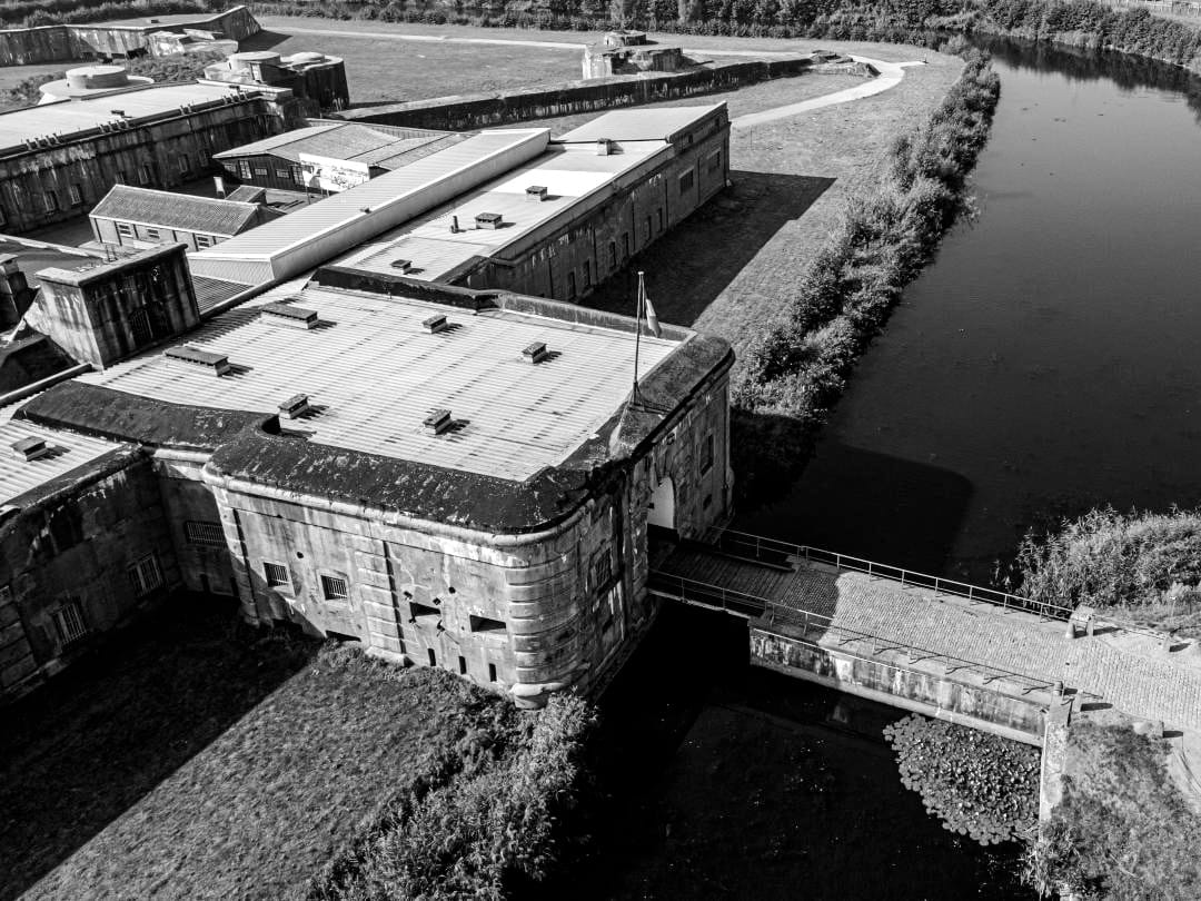 The moat around the fort, a natural barrier. While originally for defense, it became a prison wall, isolating the suffering within from the world outside.